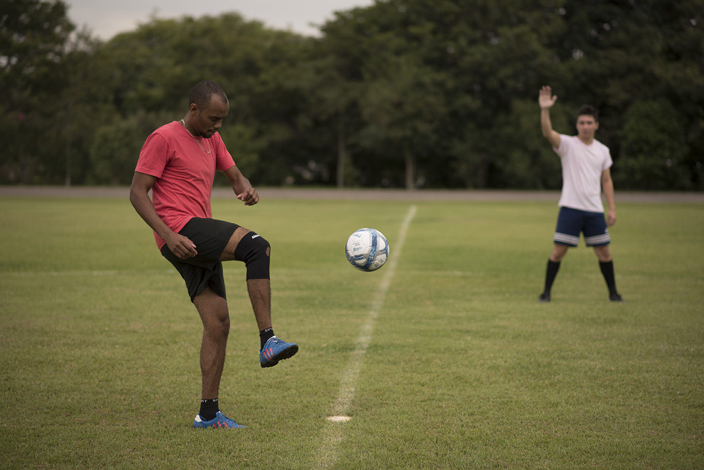 Jogador de futebol com bola em pé no joelho, jogar futebol