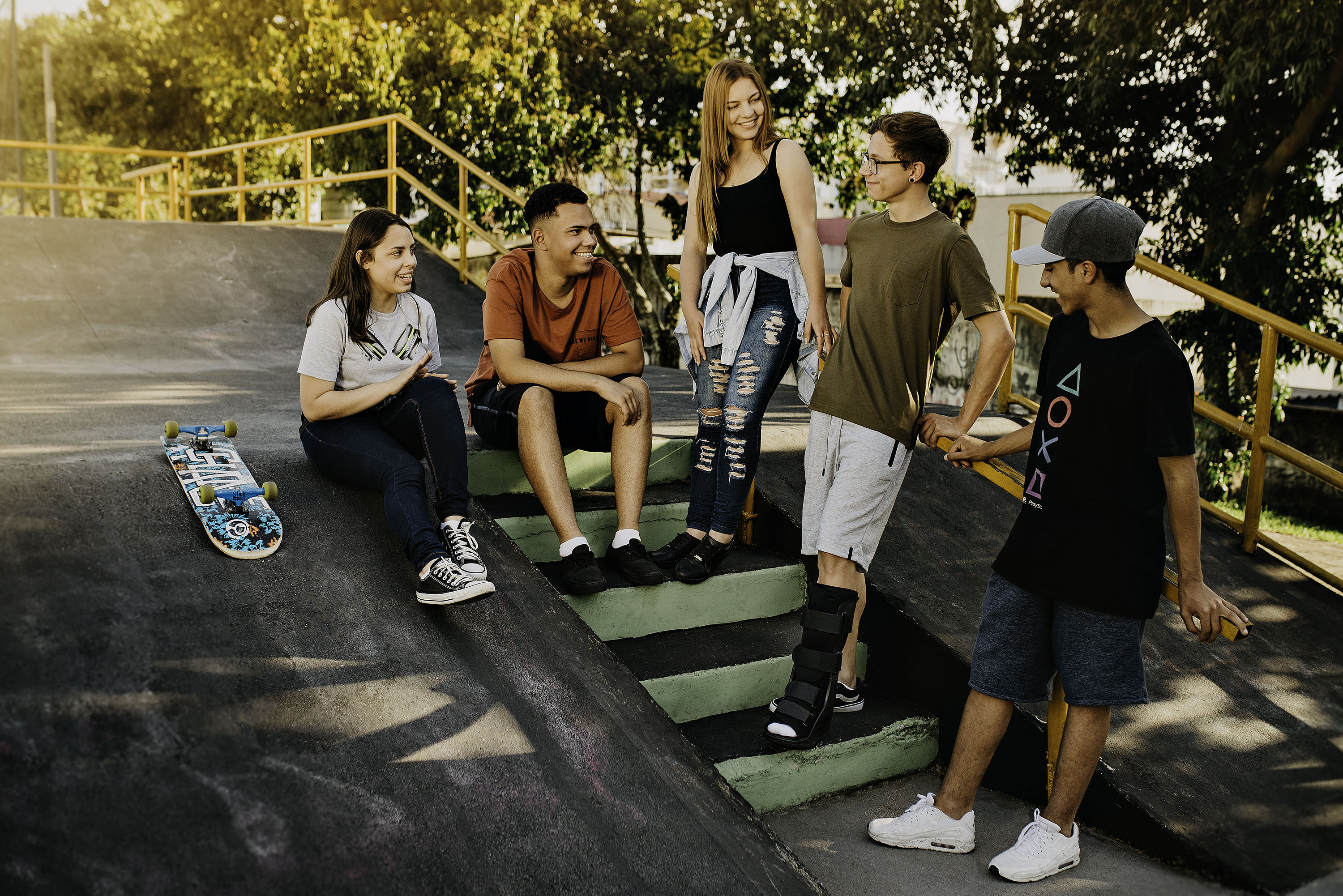 Cinco adolescentes estão conversando em uma pista de skate. Um dos meninos está utilizando a Bota Imobilizadora M1 Longa.
